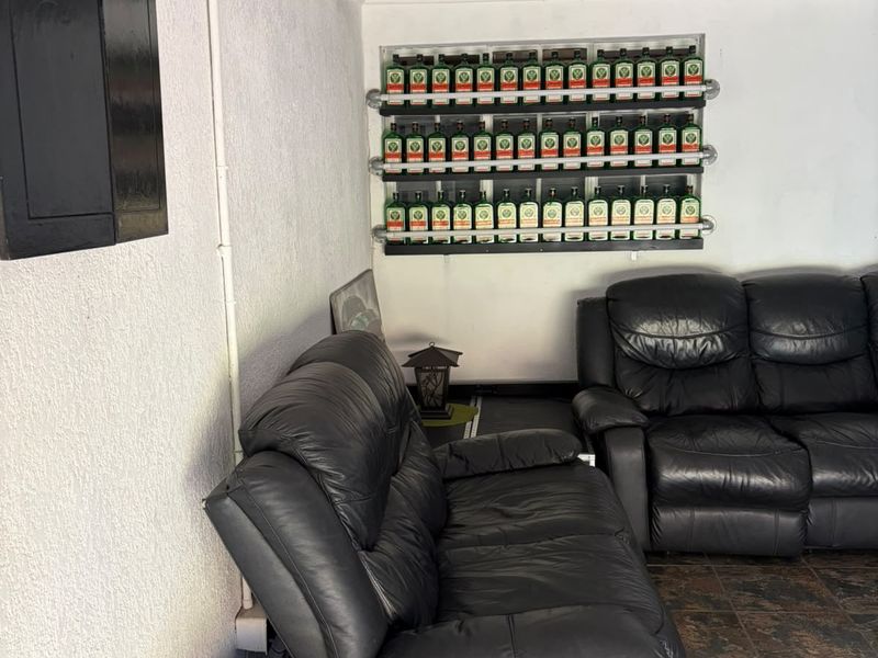 A dedicated bar area featuring built-in wall shelving and tiled flooring, currently utilized as a casual lounge space.
