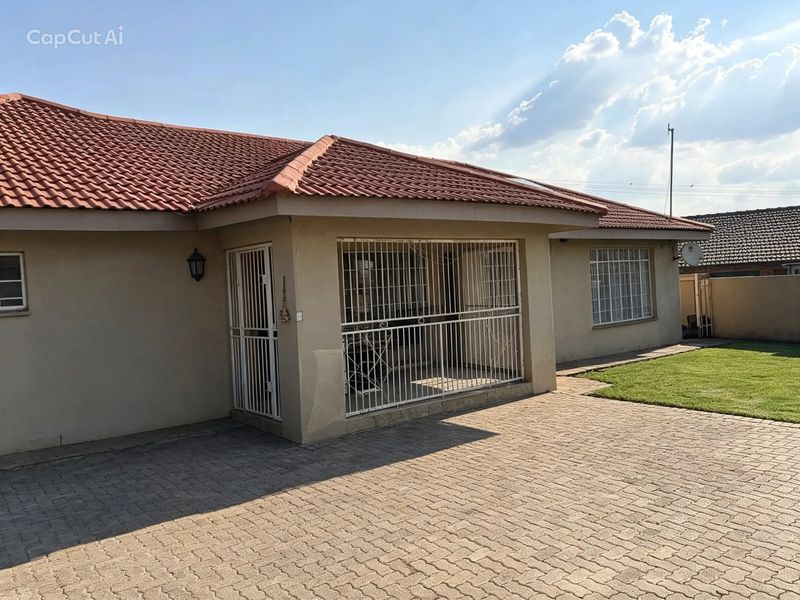 Front elevation of a single-story house featuring a tiled roof, paved driveway, and secure entrance with fitted security gates and bars.