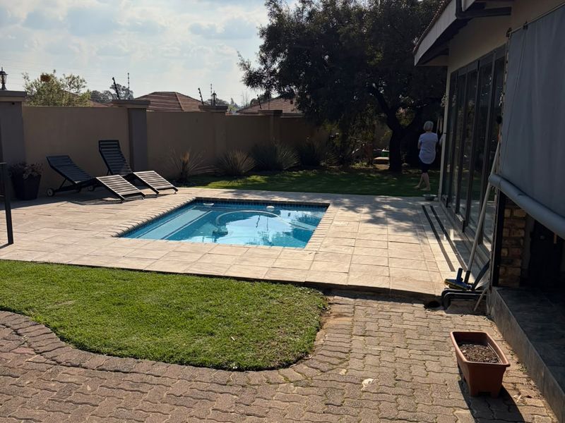 Outdoor pool area featuring a paved patio, swimming pool, and access to the home via large sliding glass doors.