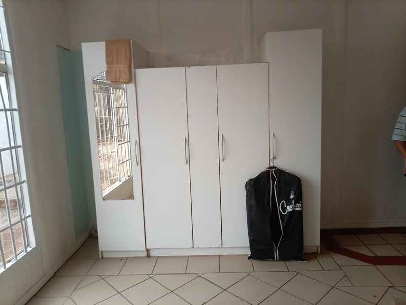 Bedroom featuring a built-in wardrobe, tiled flooring, and a glass panel door, requiring minor cosmetic repairs to the wall finishes.