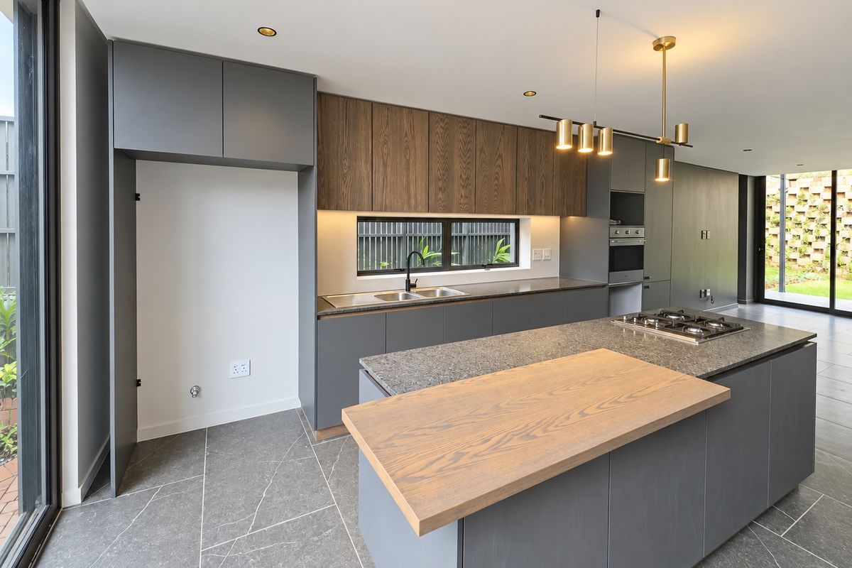 Modern kitchen featuring a large island with stone countertops, built-in oven, gas cooktop, and high-quality cabinetry with integrated lighting.