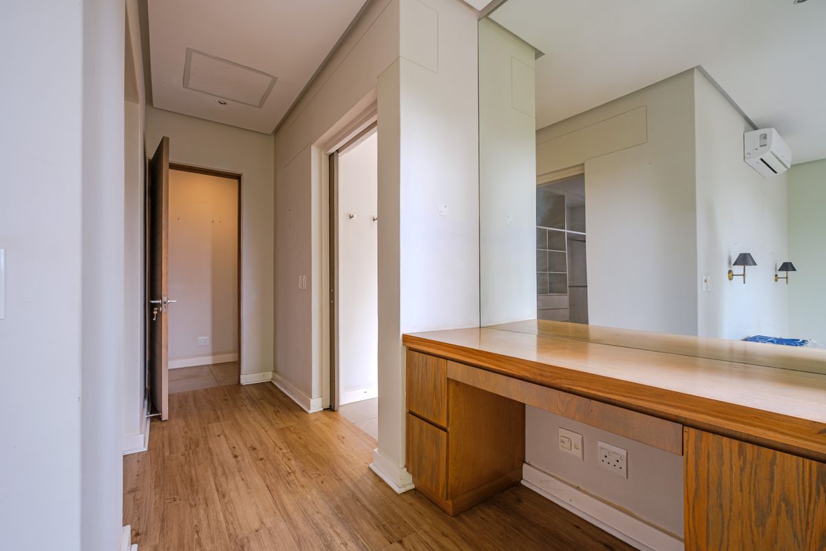 A bedroom area featuring built-in wooden vanity cabinetry, a large wall mirror, laminate flooring, and an integrated air conditioning unit.