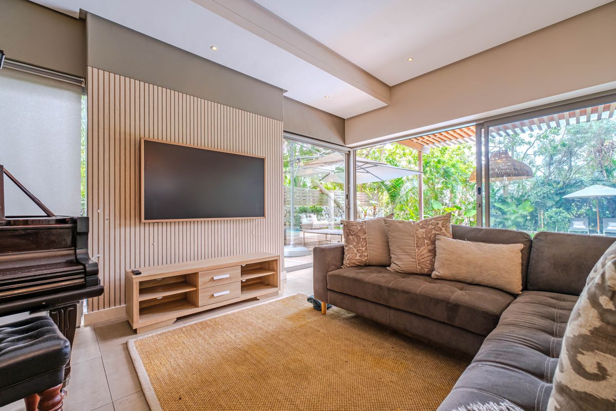 Modern living room featuring stylish slatted timber wall paneling, recessed lighting, and large sliding glass doors that provide seamless access to the outdoor area.