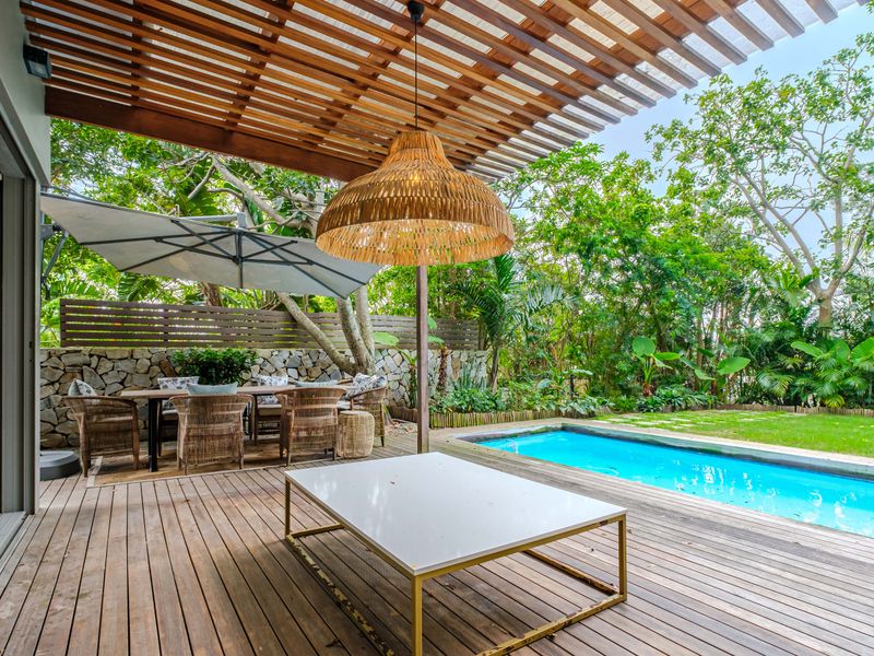 Covered timber patio featuring a pergola, overlooking a private swimming pool and landscaped garden area.