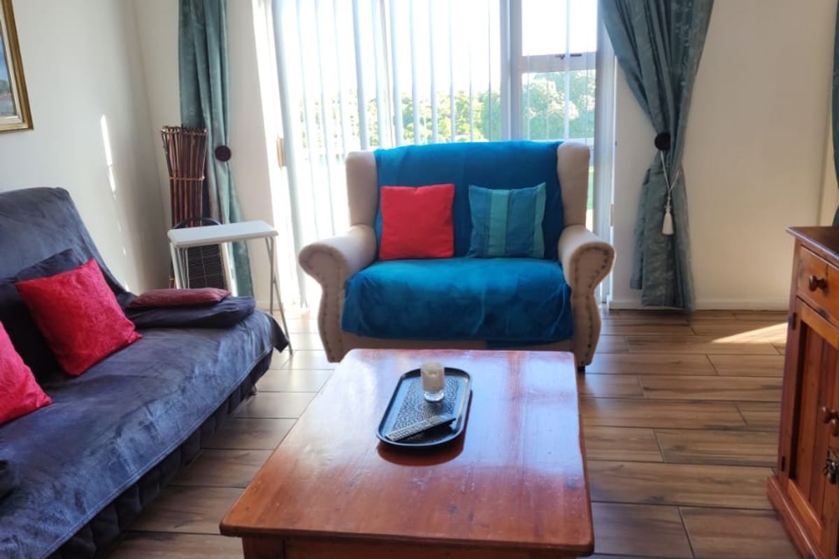 A living room featuring wood-look tiled flooring and a large sliding glass door with vertical blinds, providing natural light and access to the exterior.
