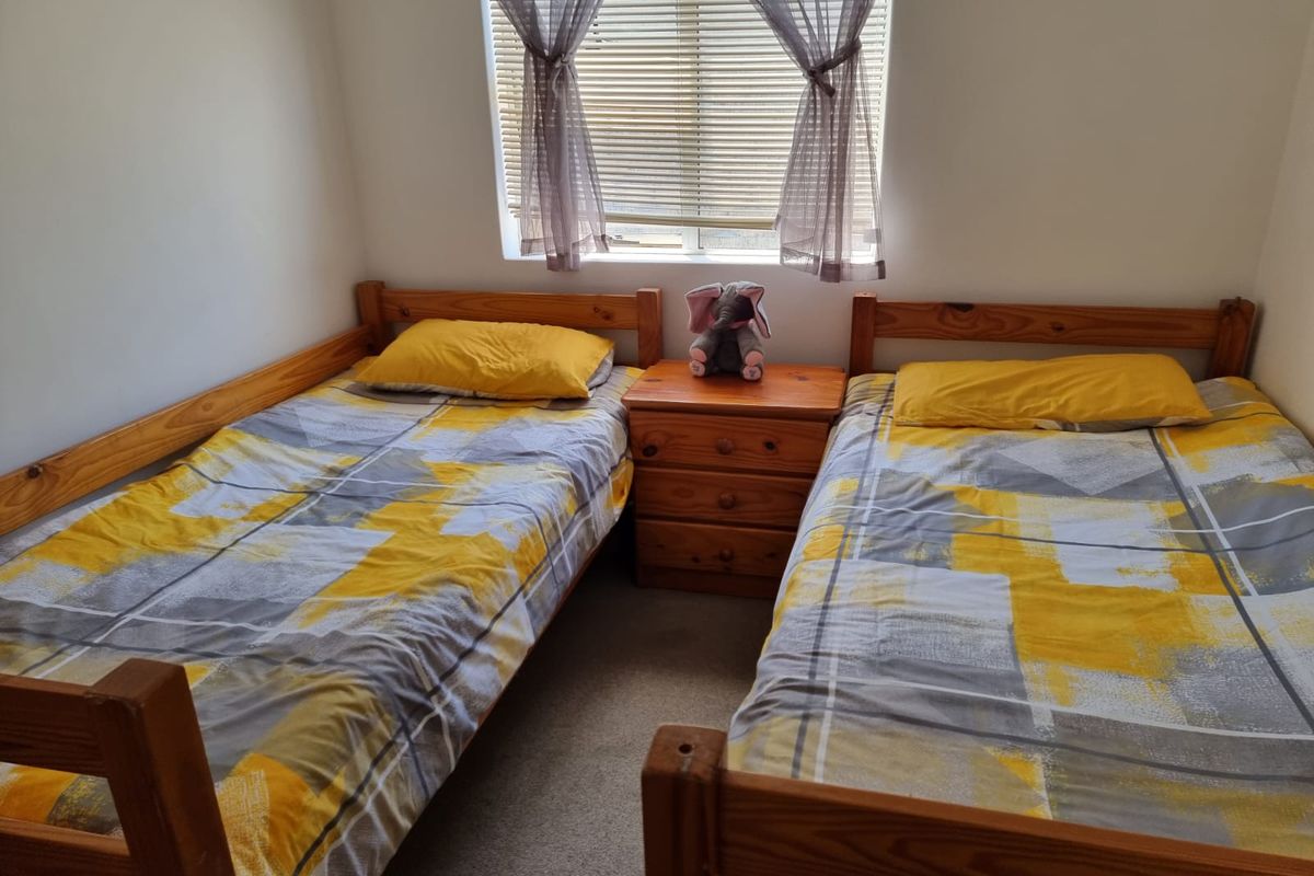 A functional bedroom featuring neutral wall finishes and a window fitted with venetian blinds.