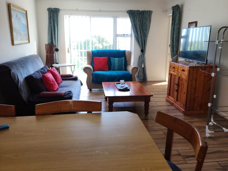 Open-plan living and dining area featuring tiled flooring and a large sliding glass door providing natural light and access to the exterior.