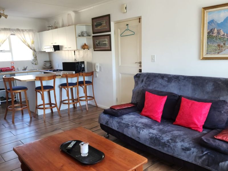 Open-plan living area featuring a functional kitchen with breakfast bar, tiled flooring, and direct access to adjacent rooms.