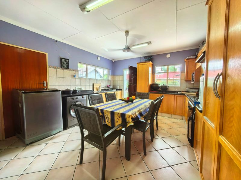 A functional kitchen featuring wooden cabinetry, tiled flooring, and a built-in oven, offering a practical layout with integrated laundry appliance space.