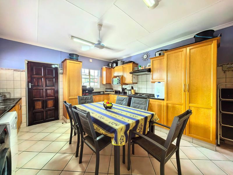 A functional kitchen featuring wooden cabinetry, tiled flooring, a built-in oven, and an extractor fan, with a dedicated dining area.