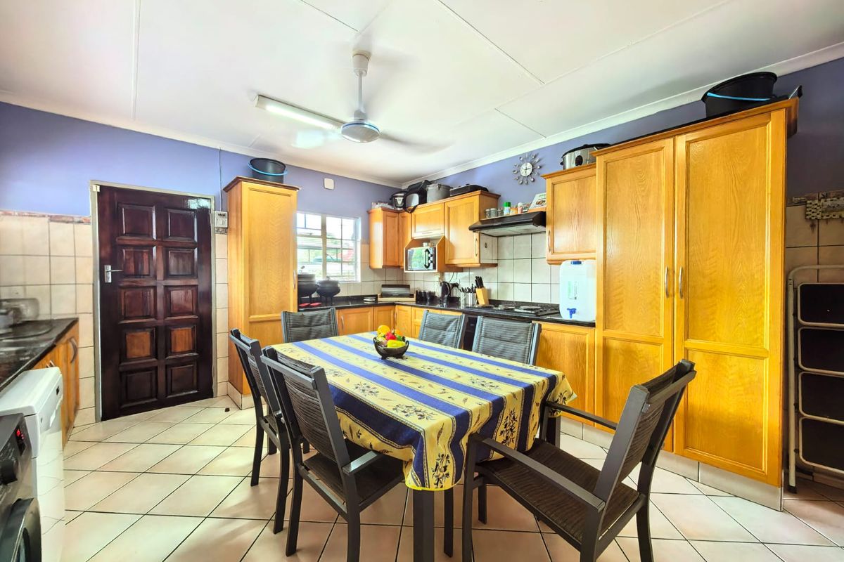 A functional kitchen featuring wooden cabinetry, tiled flooring, a built-in oven, and an extractor fan, with a dedicated dining area.