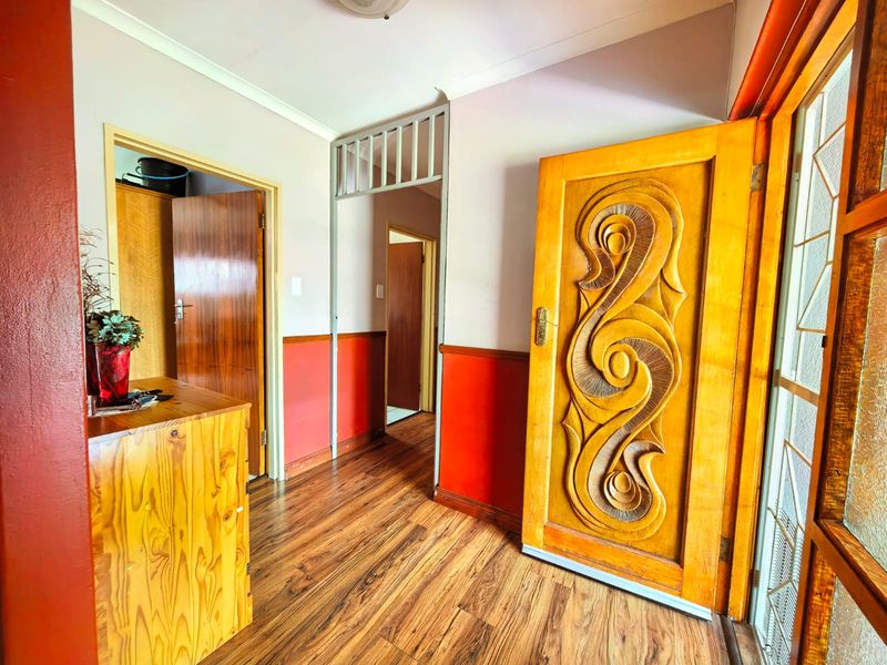 Entrance hall featuring a decorative carved wooden front door, laminate flooring, and access to internal rooms.