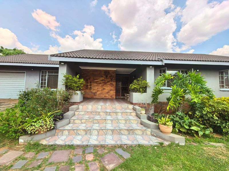 Front facade of a single-story house featuring a tiled entrance staircase, brick feature wall, and integrated planters leading to the main entrance.