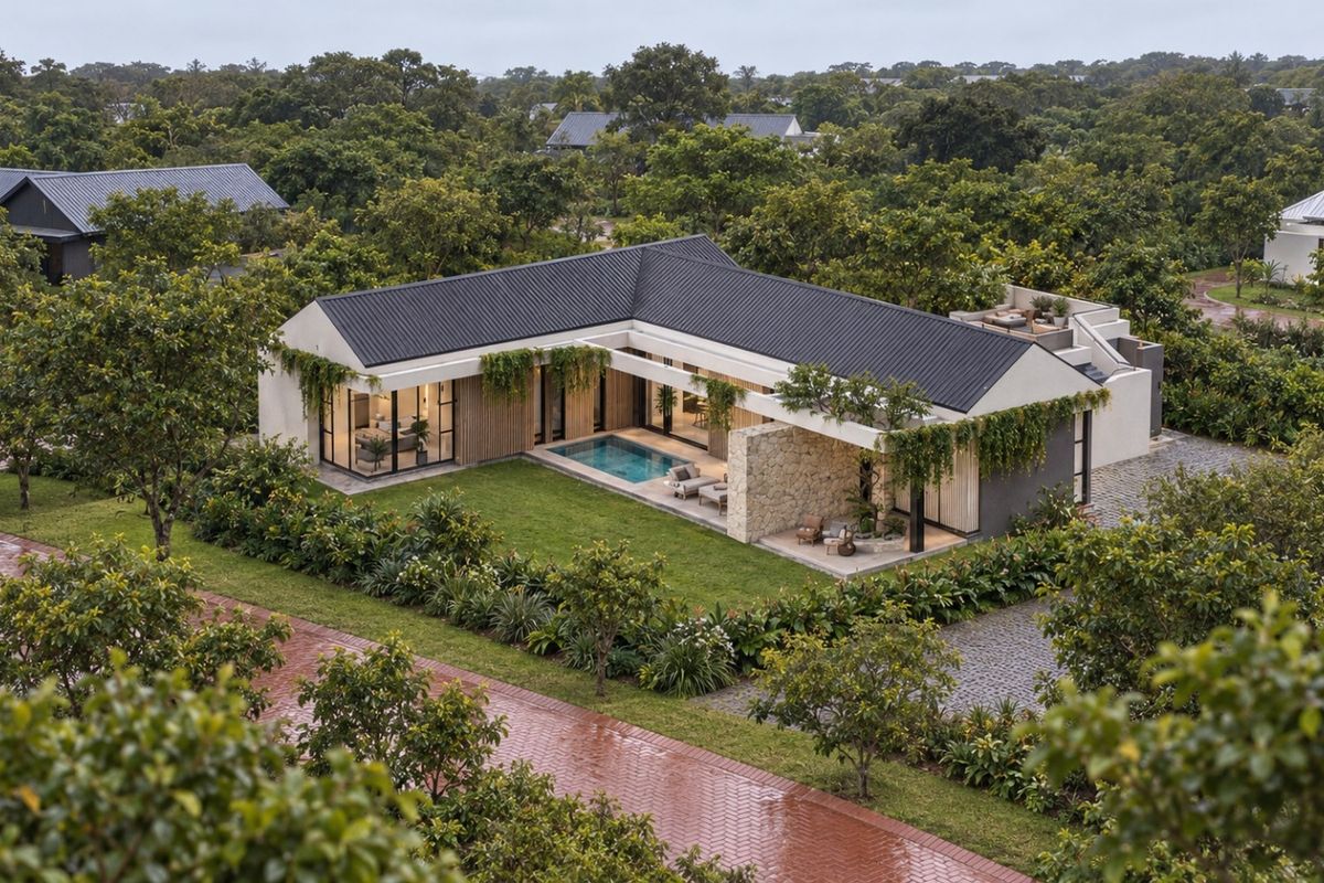Aerial view of a modern L-shaped residence featuring a private swimming pool, covered patio, stone accents, and lush landscaped surroundings.