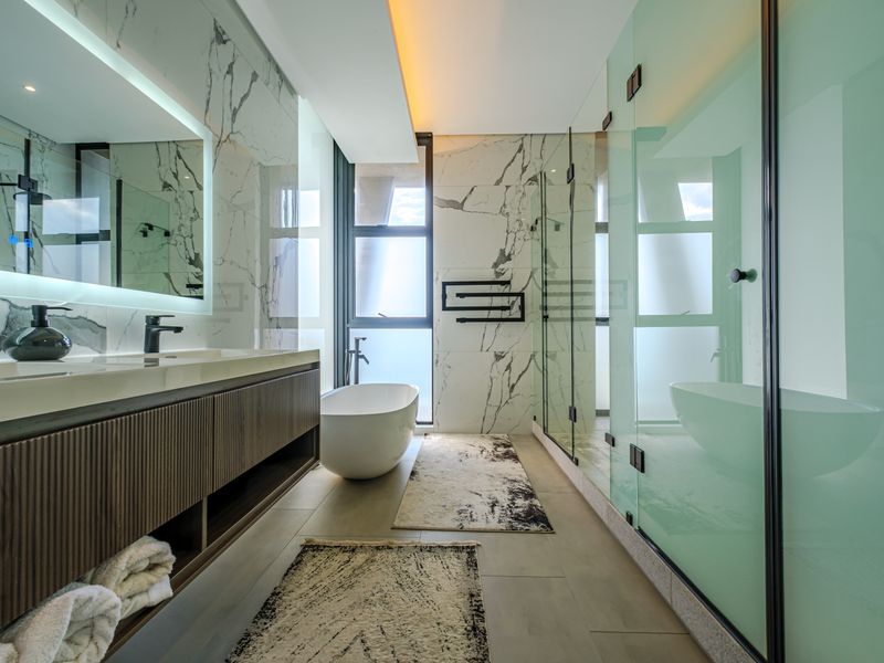 Modern luxury bathroom featuring a freestanding bathtub, double vanity with backlit mirror, and a spacious walk-in shower with high-end marble-look finishes.