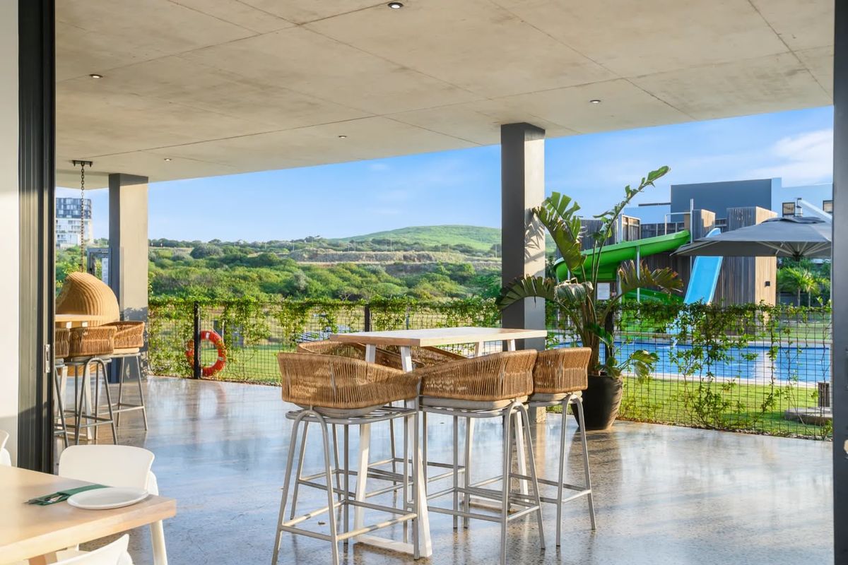 A spacious covered patio featuring a polished concrete floor and ceiling, offering views of the surrounding landscape and pool area.