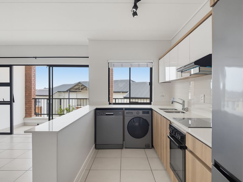 Modern kitchen featuring sleek cabinetry, stone countertops, integrated appliances, and tiled flooring, with direct access to a private balcony.