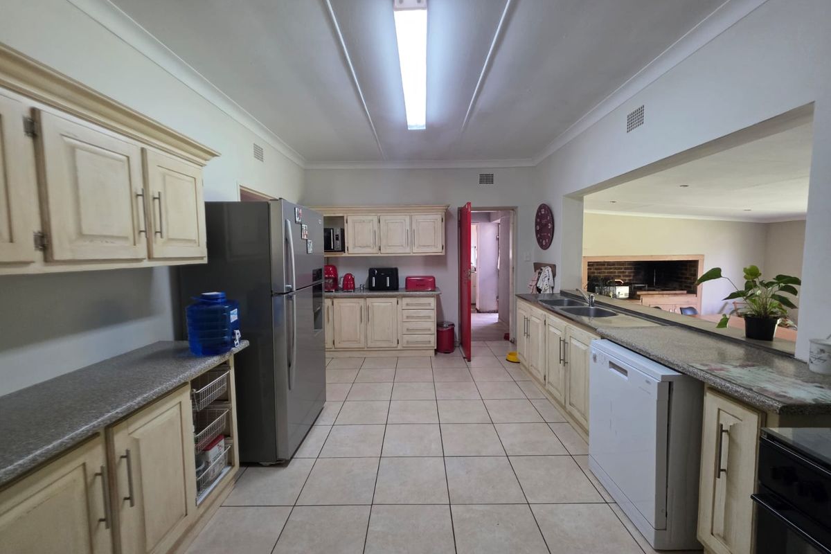 Spacious kitchen featuring ample built-in cabinetry, granite countertops, and a double sink, with an open-plan layout connecting to the adjacent living area.