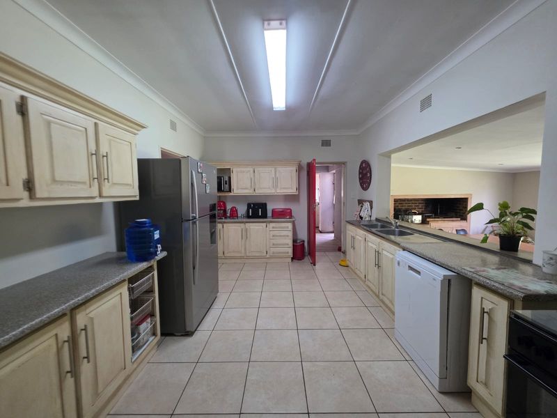 Spacious kitchen featuring ample built-in cabinetry, granite countertops, and a double sink, with an open-plan layout connecting to the adjacent living area.