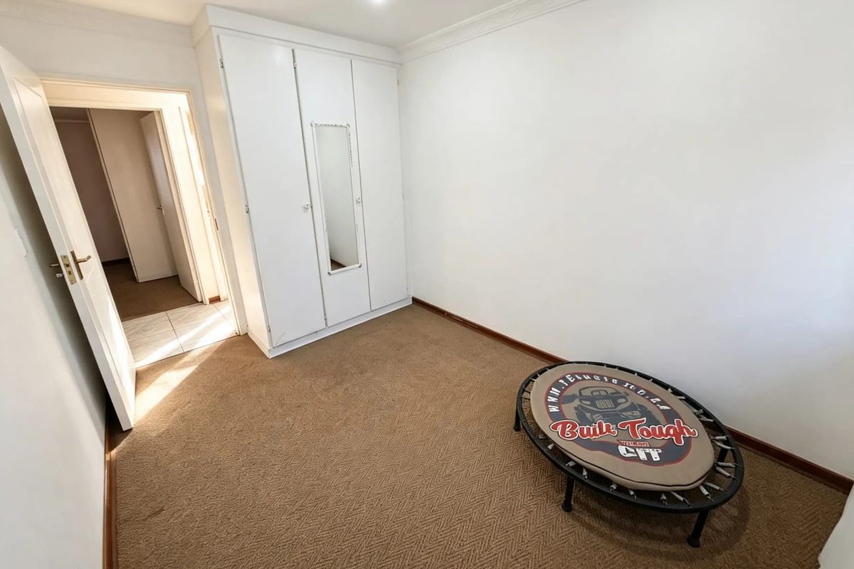 A clean, neutral bedroom featuring built-in wardrobes, carpeted flooring, and classic cove cornicing, offering a versatile space ready for personalization.
