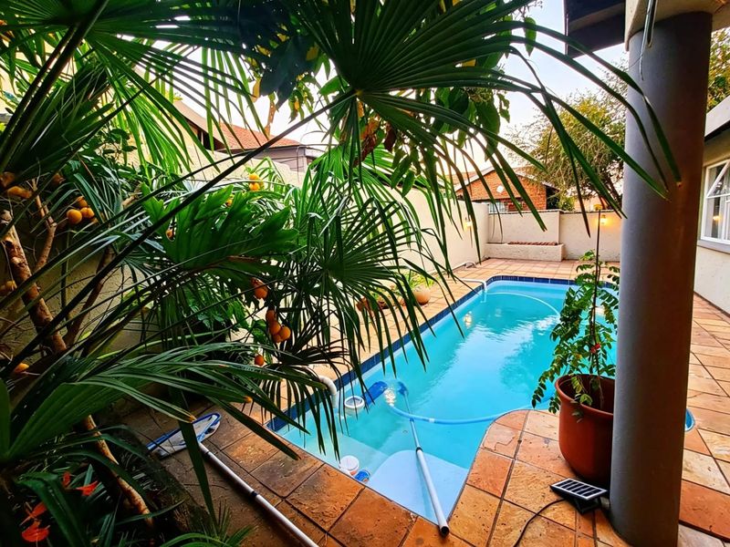 A private swimming pool area featuring a tiled patio, surrounding boundary walls, and lush tropical landscaping, providing a tranquil outdoor space.