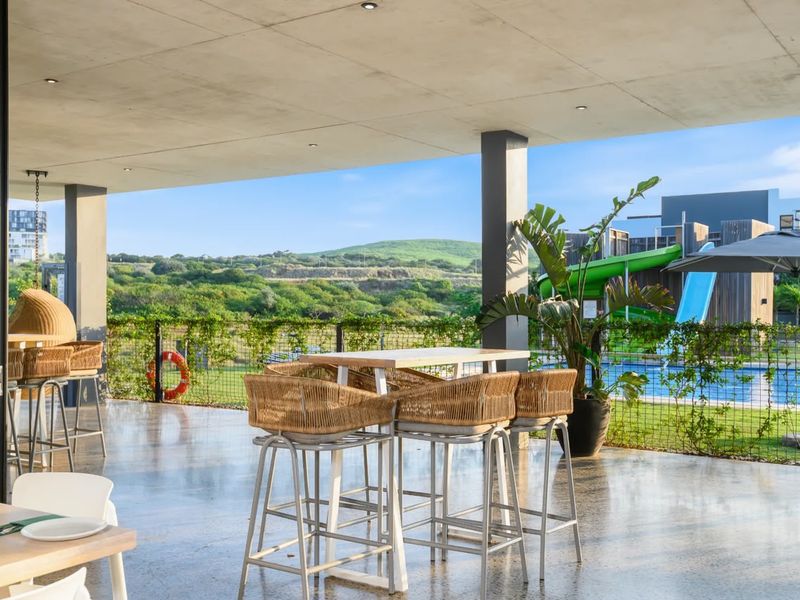 A spacious covered patio featuring a polished concrete floor and ceiling, offering views of the surrounding landscape and pool area.
