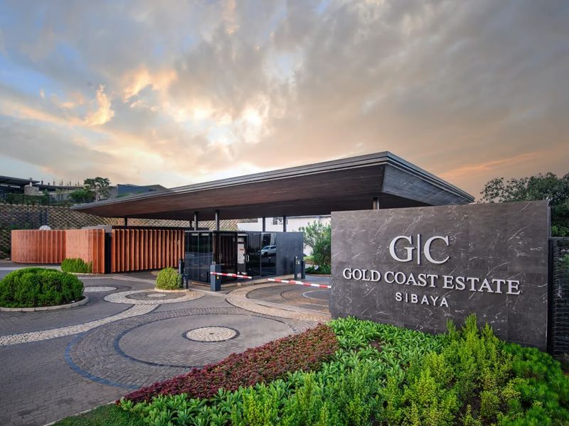 The secure entrance gatehouse of Gold Coast Estate, featuring modern architectural design, stone signage, and well-maintained landscaped surroundings.