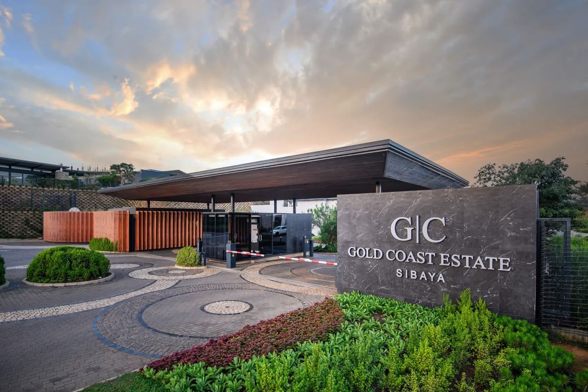 The secure entrance gatehouse of Gold Coast Estate, featuring modern architectural design, stone signage, and well-maintained landscaped surroundings.