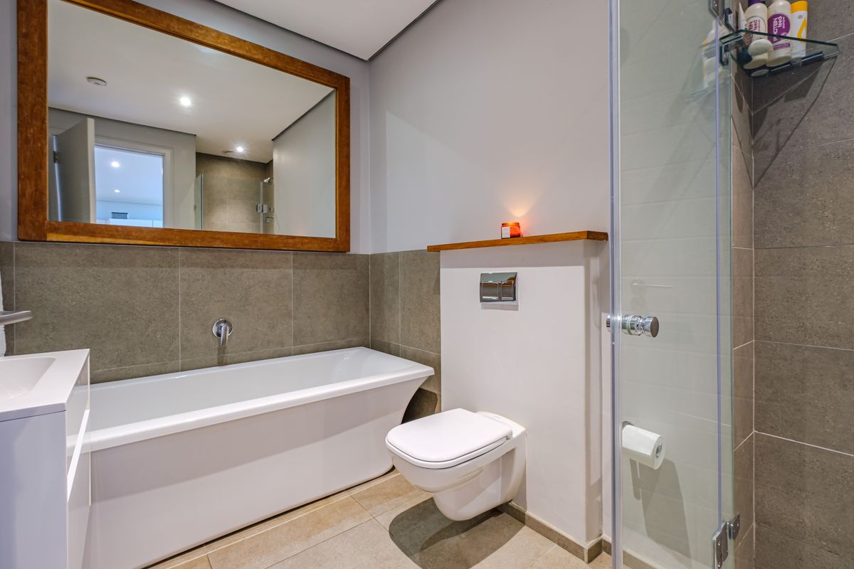 Modern bathroom featuring a freestanding bathtub, wall-mounted toilet with concealed cistern, glass shower enclosure, and contemporary tiled finishes.