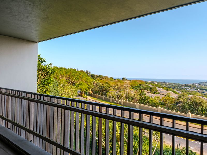 A covered balcony featuring a timber balustrade, offering elevated views of the surrounding landscape and distant coastline.