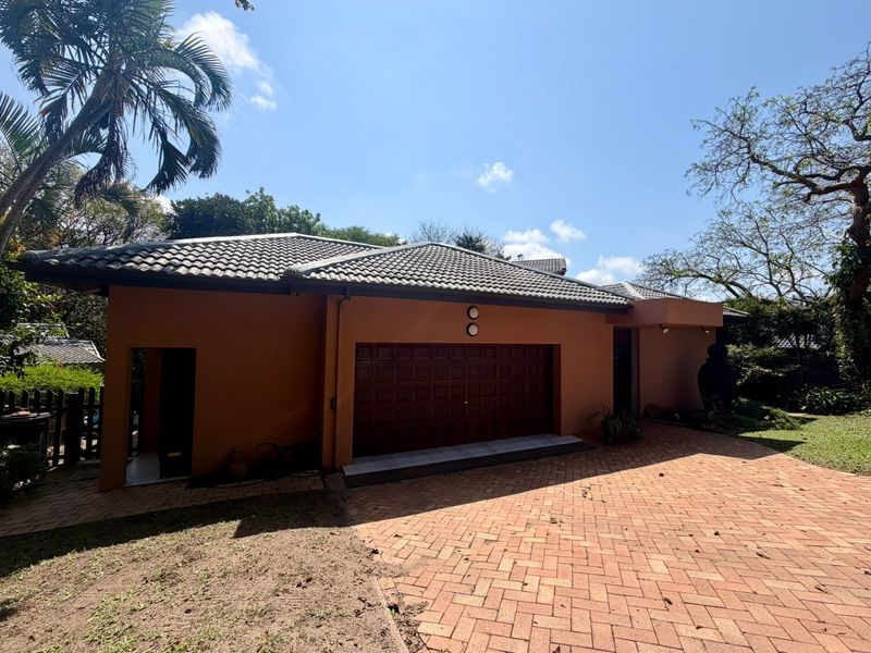 Front exterior view of the house featuring a paved driveway, garage access, and a well-maintained tiled roof structure.