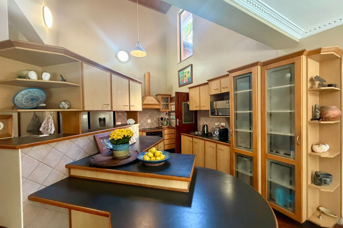 Spacious kitchen featuring vaulted ceilings, extensive built-in cabinetry, integrated appliances, and a functional layout with a central breakfast bar area.