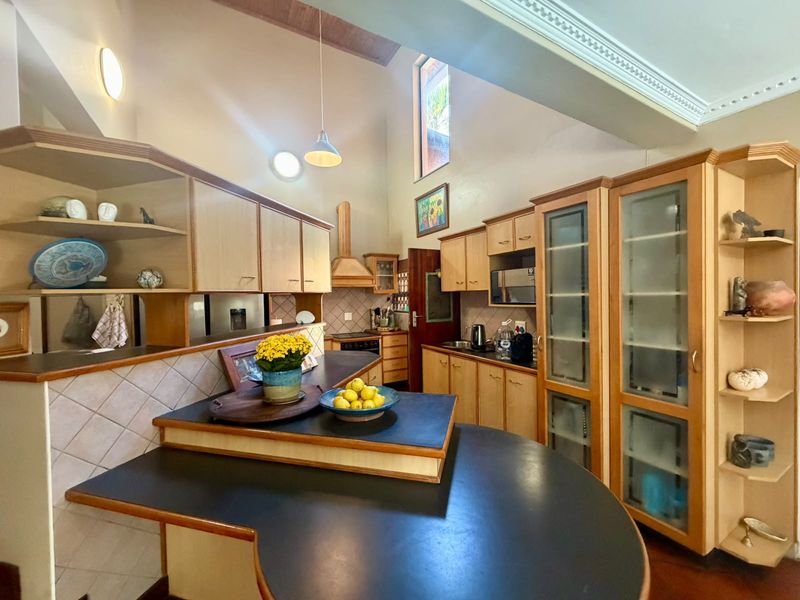 Spacious kitchen featuring vaulted ceilings, extensive built-in cabinetry, integrated appliances, and a functional layout with a central breakfast bar area.