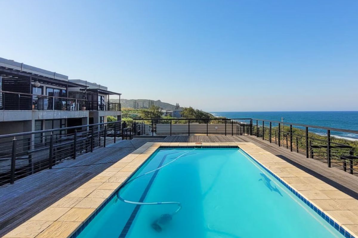 Outdoor pool area featuring timber decking, metal balustrades, and expansive ocean views, providing a scenic space for relaxation and entertainment.
