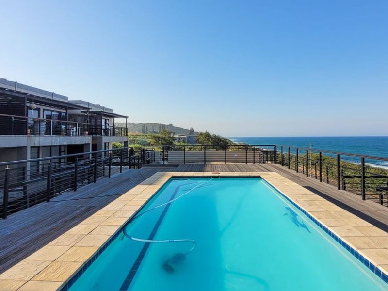 Outdoor pool area featuring timber decking, metal balustrades, and expansive ocean views, providing a scenic space for relaxation and entertainment.