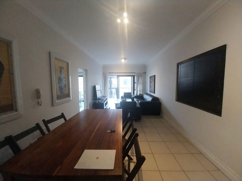 Open-plan living and dining area featuring tiled flooring, neutral walls, and a sliding glass door leading to an outdoor space.