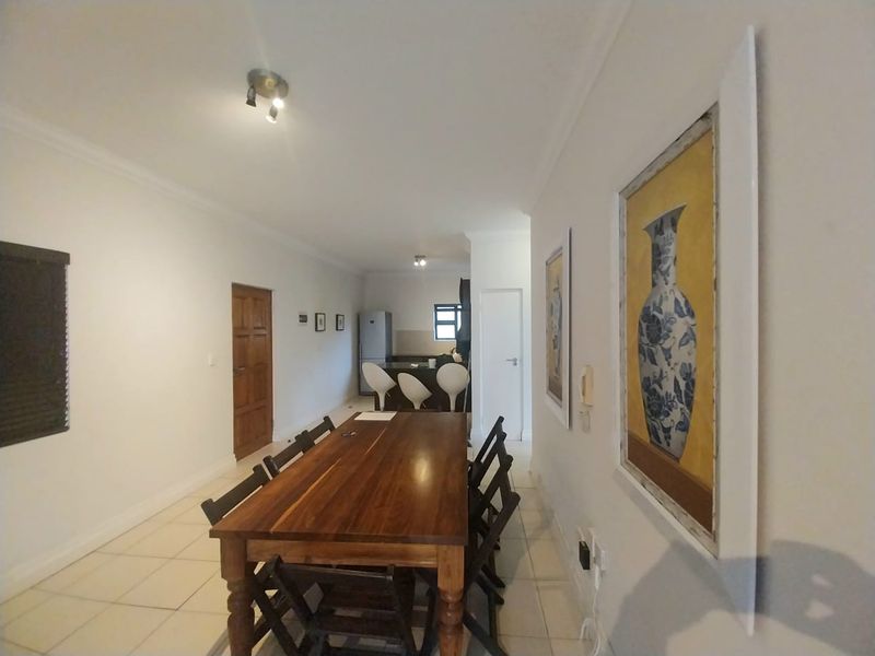 Open-plan living and dining area featuring tiled flooring, neutral walls, and a functional kitchen space with built-in cabinetry.