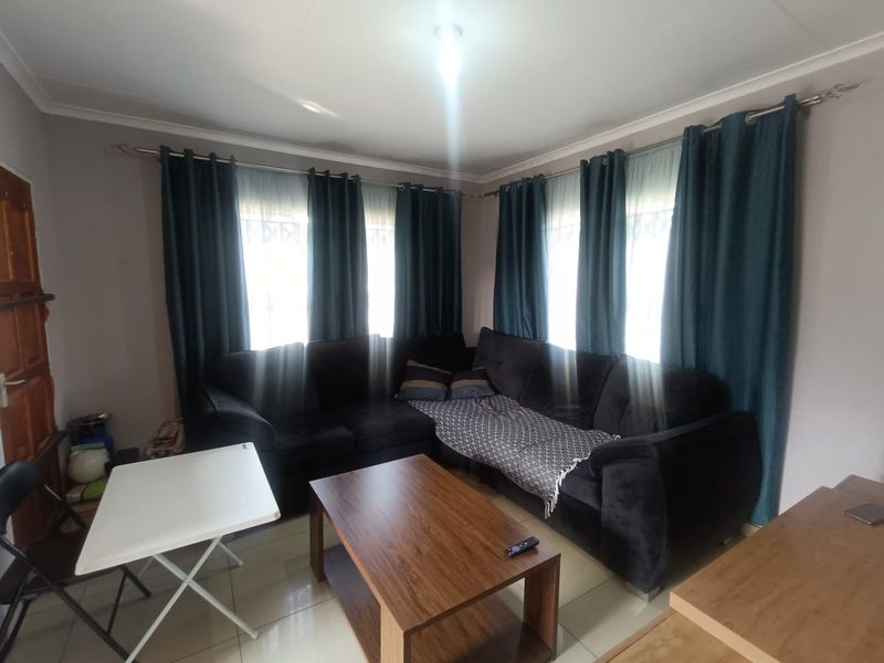 A living room featuring tiled flooring, window security bars, and curtain rods, providing a functional space for relaxation.