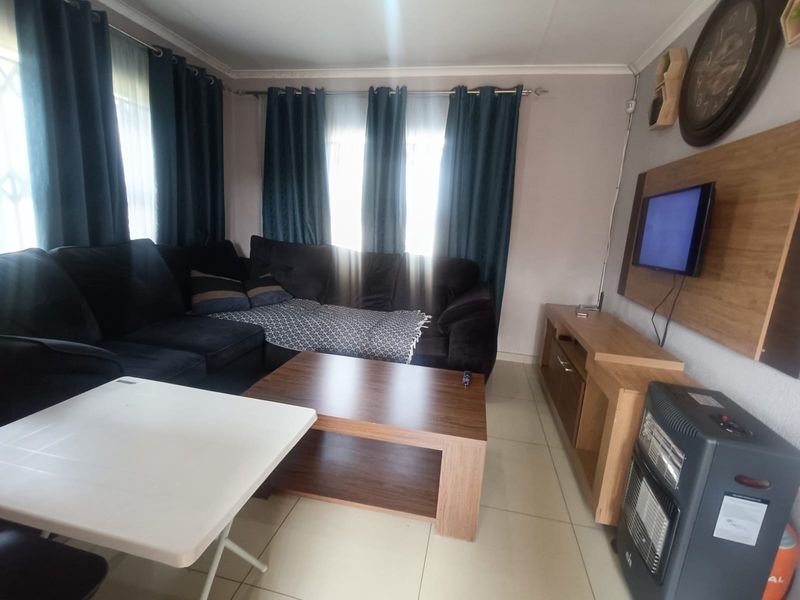A functional living room featuring tiled flooring and a wall-mounted television panel, providing a comfortable and practical space for relaxation.