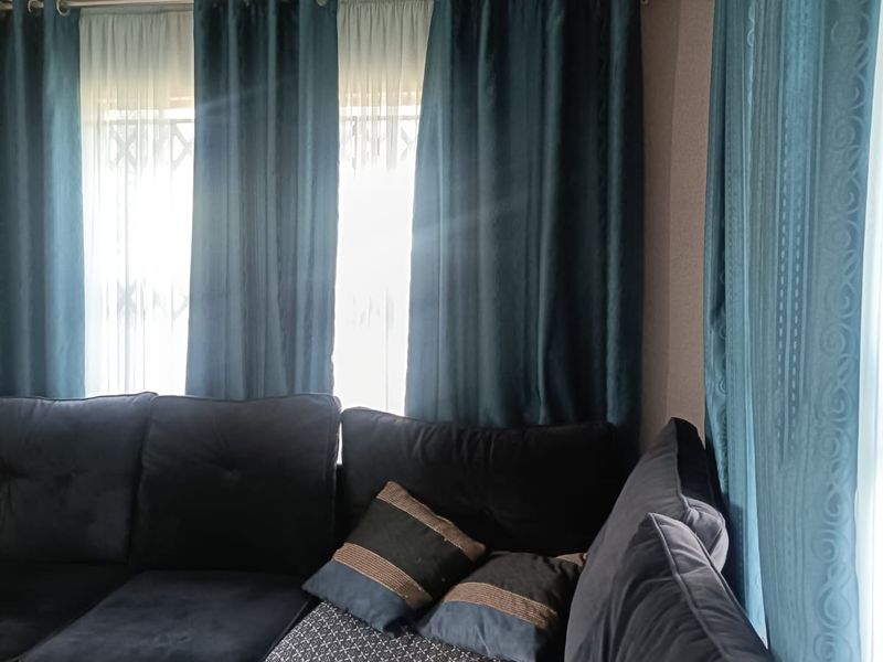 A living room area featuring tiled flooring and window treatments with curtain rods.