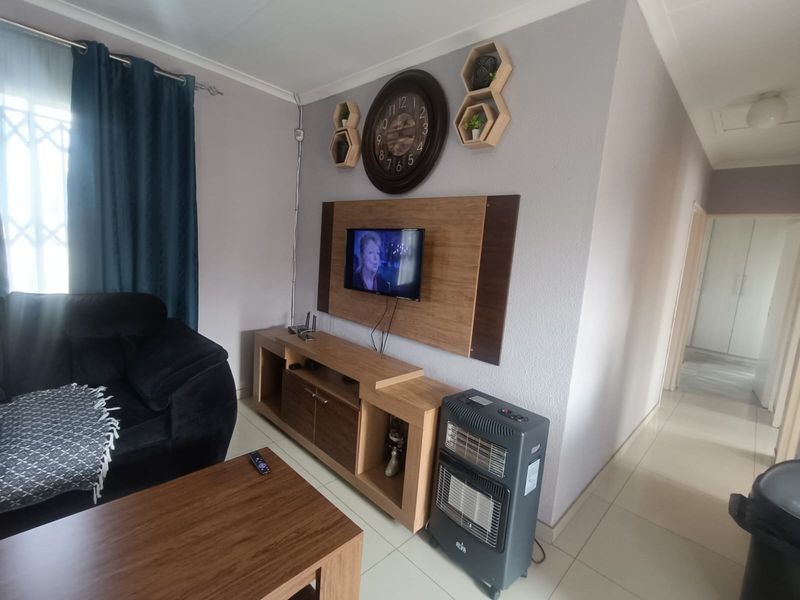 A living room area featuring tiled flooring and a decorative wall-mounted panel for media equipment.