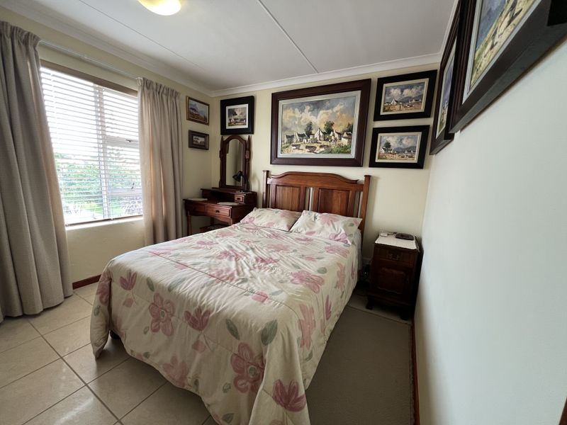 A well-lit bedroom featuring tiled flooring, venetian blinds, and neutral wall finishes, providing a comfortable and functional sleeping space.