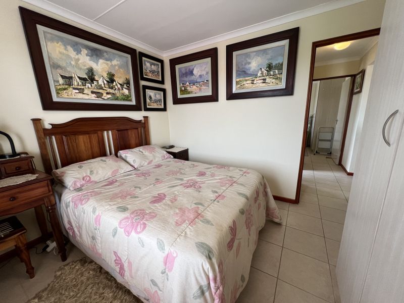A bedroom featuring tiled flooring, cove cornicing, and a built-in wardrobe, with a doorway leading to an adjacent hallway.
