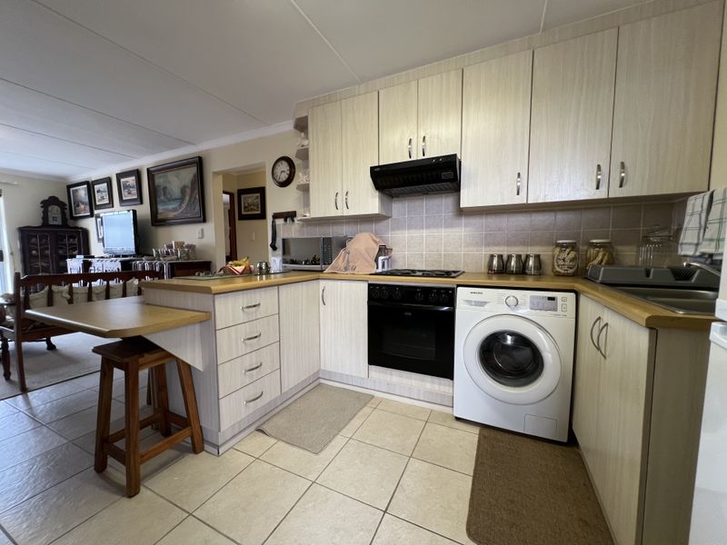 Open-plan kitchen featuring laminate cabinetry, built-in oven, hob, extractor fan, and integrated washing machine, seamlessly flowing into the adjacent living area.