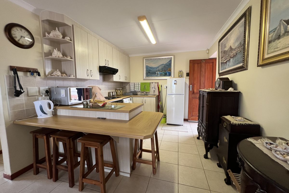 A functional kitchen featuring light-toned built-in cabinetry, a breakfast bar, tiled flooring, and a tiled backsplash, offering a practical layout for daily use.