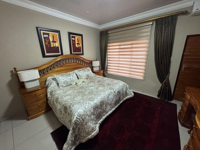 A well-maintained bedroom featuring tiled flooring, crown molding, and an integrated air conditioning unit with window treatments.