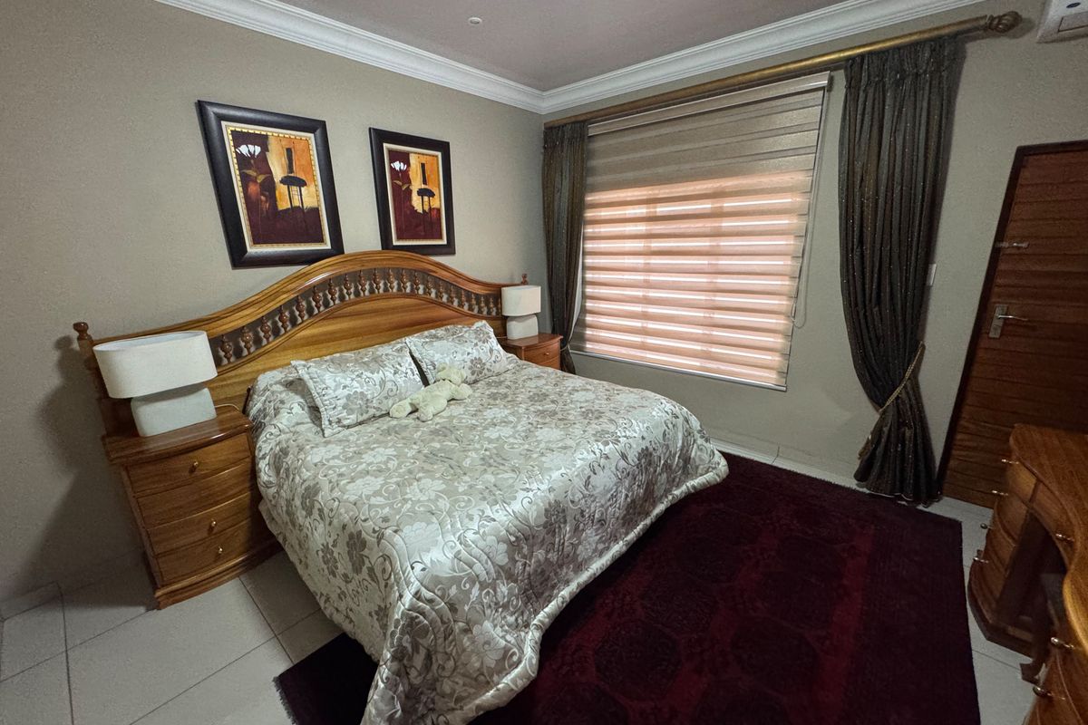 A well-maintained bedroom featuring tiled flooring, crown molding, and an integrated air conditioning unit with window treatments.