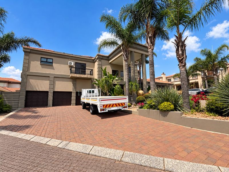 Front elevation of a multi-story residence featuring a paved driveway, double garage, and a covered entrance with balcony above.