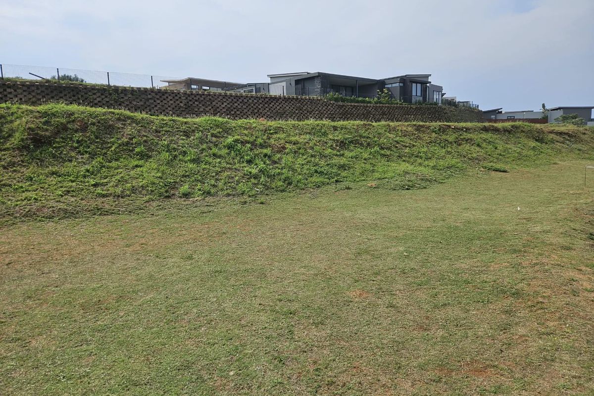 A view of the vacant residential land featuring a grassed slope and a structured retaining wall along the upper boundary.
