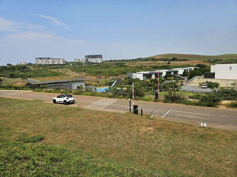 Elevated view overlooking a residential estate with paved roads, security access points, and surrounding landscaped terrain.
